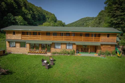 a large wooden house with a lawn in front of it at Natural e Simplu in Petroşani