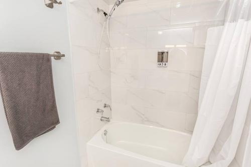 a white bathroom with a shower and a white tub at Upscale 3BR/2.5BATH House +Games room and Yard! in Mississauga