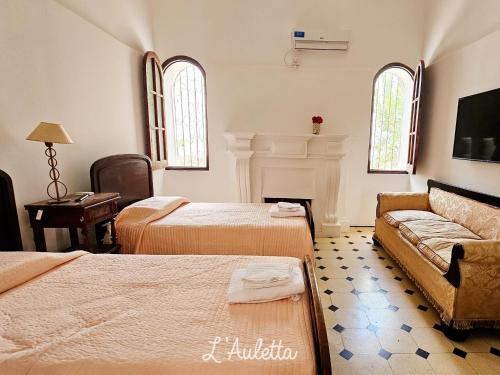 um quarto de hotel com duas camas e um sofá em L' Auletta em Cafayate