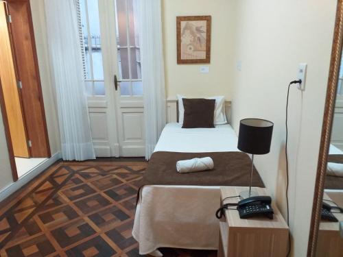 a small room with a bed and a telephone at Hotel Praça da Matriz in Porto Alegre