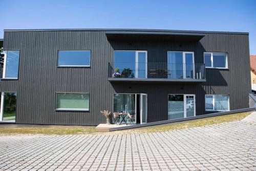 a black house with a balcony on a brick driveway at Järvevaatega apartment in Viljandi