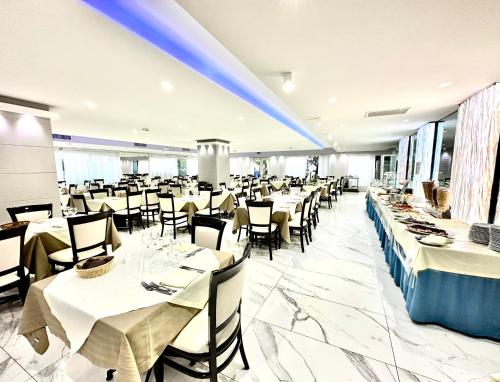 un comedor con mesas y sillas blancas en Hotel Blu en Porto Cesareo