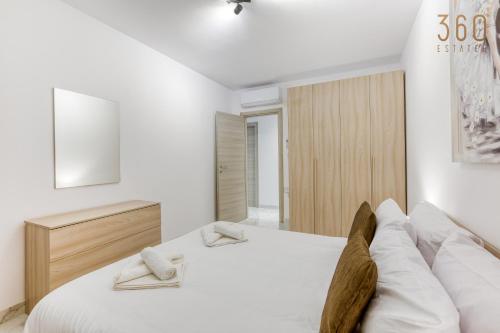 a white bedroom with a bed with two feet on it at Beautiful 3BR Triplex penthouse with Hot-Tub by 360 Estates in Il-Gżira