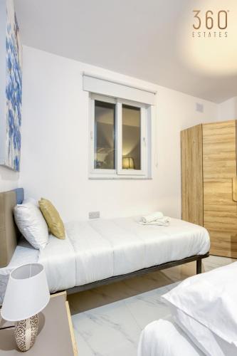 a white room with a bed and a window at Beautiful 3BR Triplex penthouse with Hot-Tub by 360 Estates in Il-Gżira