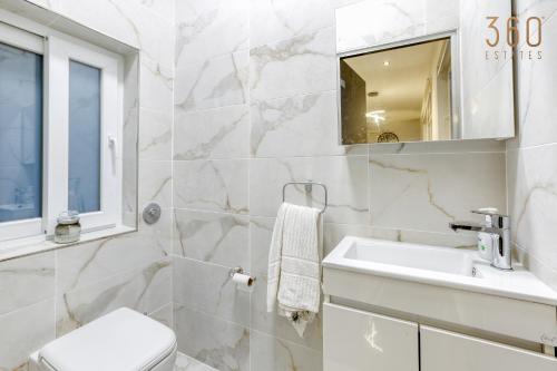 a bathroom with a sink and a toilet and a mirror at Beautiful 3BR Triplex penthouse with Hot-Tub by 360 Estates in Il-Gżira