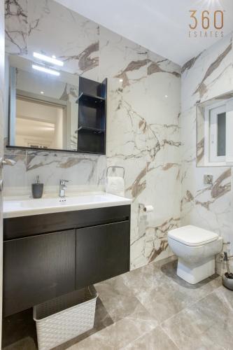 a bathroom with a sink and a toilet and a mirror at Beautiful 3BR Triplex penthouse with Hot-Tub by 360 Estates in Il-Gżira