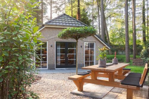 a picnic table and bench in front of a house at Veluwe vakantiehuis - Bosuil Lodge in Lunteren