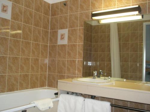 uma casa de banho com um lavatório, uma banheira e um espelho. em Hotel Restaurant Le Pavillon Carina em Gap