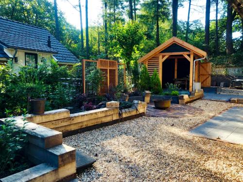 a garden with a small cabin in the woods at Veluwe vakantiehuis - Bosuil Lodge in Lunteren