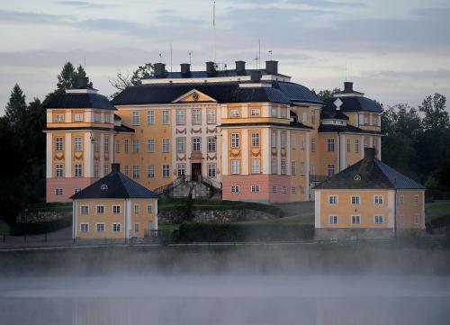 un grand bâtiment avec de nombreuses fenêtres en face de l'eau dans l'établissement Ericsbergs Slott, à Katrineholm
