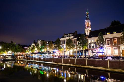 a city lit up at night with a clock tower at Gr8 Hotel Breda in Breda