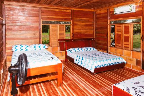 two beds in a room with wooden walls at Casa Campestre Reina María in San José del Guaviare