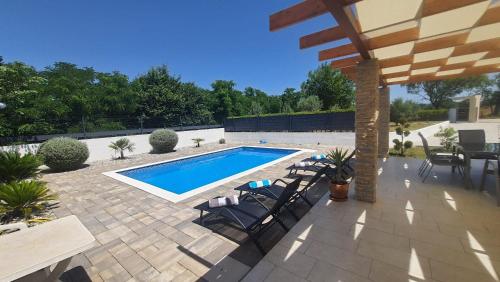 un patio con piscina, sillas y mesa en Happy House en Zadar