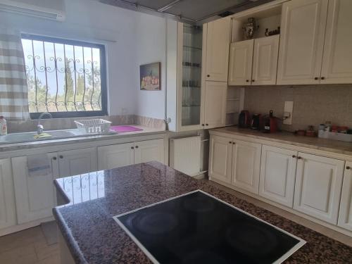 a kitchen with white cabinets and a black counter top at Villa in Trilofos-close to the beach in Thessaloniki