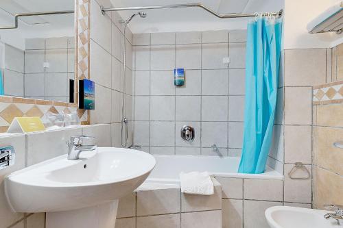a bathroom with a sink and a tub and a toilet and a sink at Hotel Carvoeiro Plaza in Carvoeiro