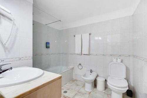 a white bathroom with a sink and a toilet at Hotel Carvoeiro Plaza in Carvoeiro