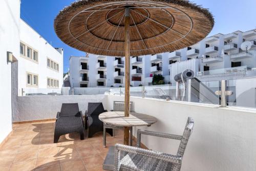 a patio with a table and chairs and an umbrella at Hotel Carvoeiro Plaza in Carvoeiro