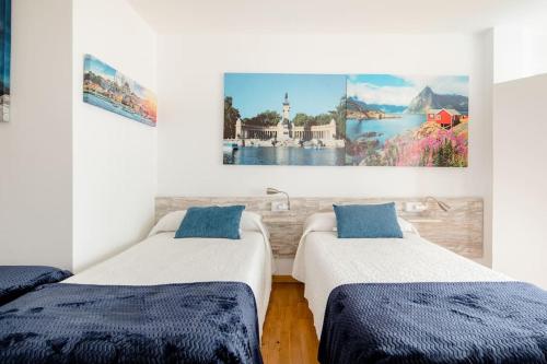 2 camas en una habitación con pinturas en la pared en Pension Myriam O PEDROUZO, en O Pedrouzo