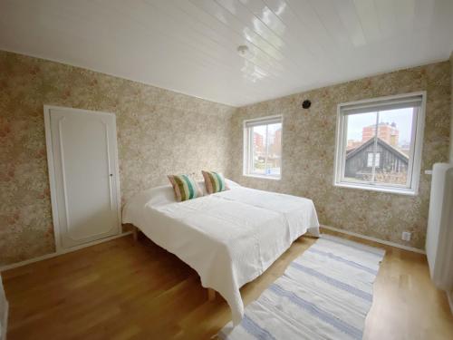 een slaapkamer met een wit bed en 2 ramen bij Holiday home in central Hoganas in Höganäs