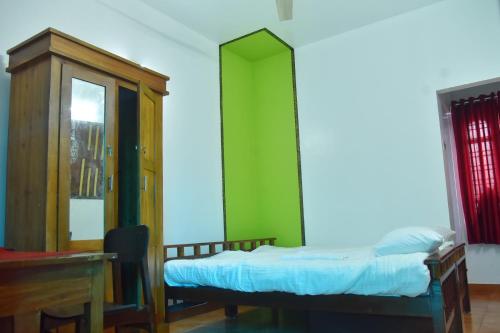 a room with a bed and a cabinet and a desk at Suryas Rooms in Varkala
