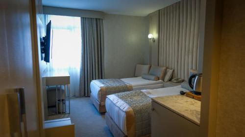a hotel room with two beds and a couch at Kervansaray Bursa City Hotel in Bursa