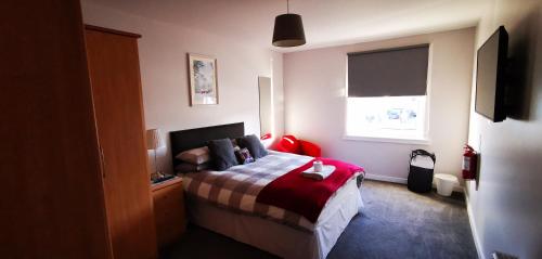 1 dormitorio con cama y ventana en Newtown Apartments en Boʼness