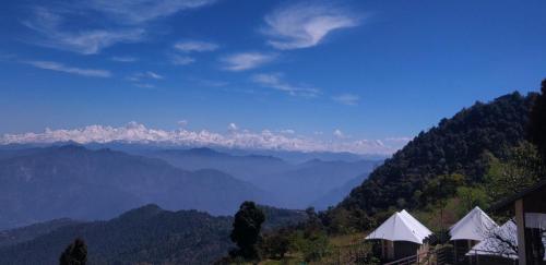 a view of a mountain valley with tents in the foreground at The Bugyal in Kanatal