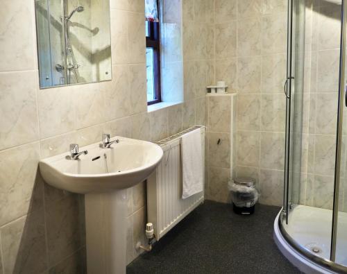 a white bathroom with a sink and a shower at Ashfield House in Pateley Bridge