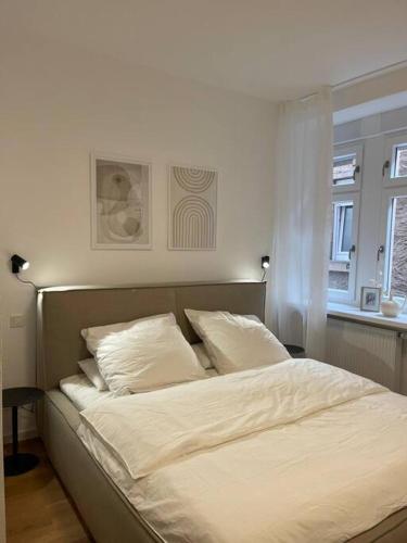 Una cama con sábanas blancas y almohadas en un dormitorio en Stilvolle Ferienwohnung: Alte Apotheke in Ürzig en Ürzig