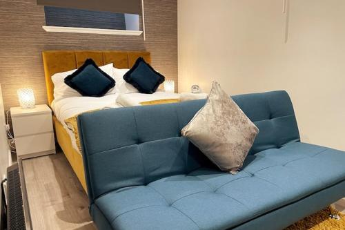 una cama con almohadas y un sofá azul en una habitación en LOVELY 3 BEDROOM APARTMENT WITH PRIVATE GARDEN IN EDINBURGH CITY CENTRE, en Edimburgo