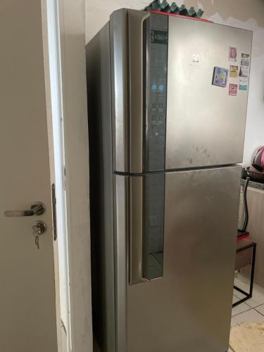 einem Kühlschrank aus Edelstahl in einer Küche neben einer Tür in der Unterkunft Quarto em frente moradia unicamp in Campinas
