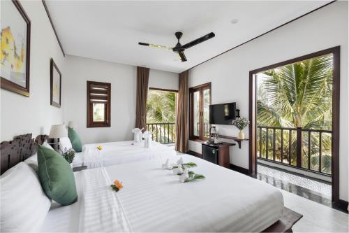 a bedroom with two beds and a large window at Mayci Boutique Hotel Hoi An in Hoi An