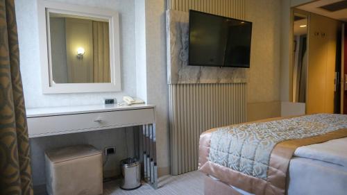 1 dormitorio con cama, espejo y TV en Kervansaray Bursa City Otel, en Bursa