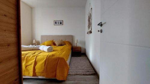 - une chambre avec un lit et une couverture jaune dans l'établissement Apartman Iris Srebrno jezero, à Veliko Gradište