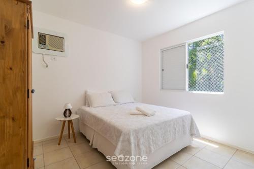 a white bedroom with a bed and a window at Belo apto agradável em Lagoa da Conceição DET0024 in Florianópolis