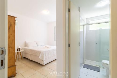 a bedroom with a bed and a glass shower at Belo apto agradável em Lagoa da Conceição DET0024 in Florianópolis