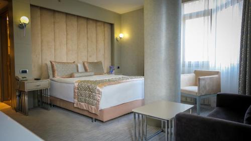 ブルサにあるケルバンサレイ ブルサ シティ オテルの大きなベッドと椅子が備わるホテルルームです。