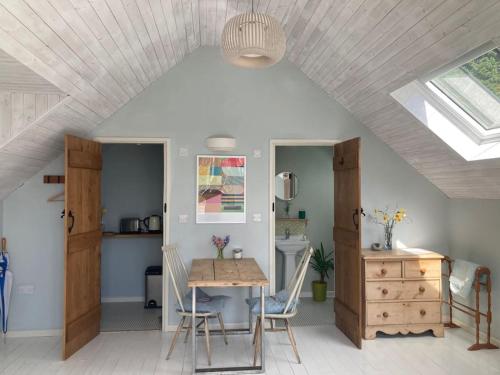 a dining room with a table and chairs and a ceiling at Bright, airy Annex in village with stunning views in Stroud