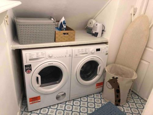 a laundry room with a washing machine and a chair at Beautiful 2 bedroom garden flat in great location in Bristol
