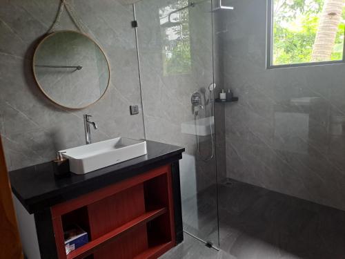 a bathroom with a sink and a shower with a mirror at MAYURA BALI VILLA in Munduk