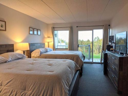 a hotel room with two beds and a balcony at Cute Lower Level Cedar Lodge Room with Balcony & Lake Views! in Laconia