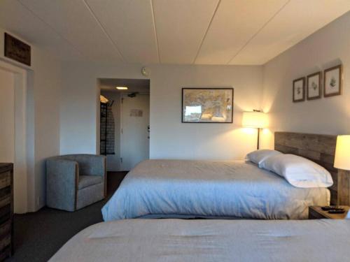 a bedroom with a bed and a chair and a lamp at Cute Lower Level Cedar Lodge Room with Balcony & Lake Views! in Laconia