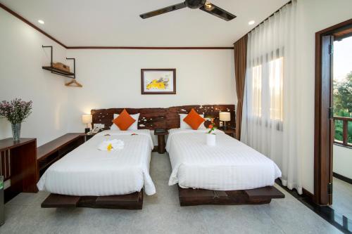 a bedroom with two beds and a window at Mayci Boutique Hotel & Restaurant by Amber in Hoi An