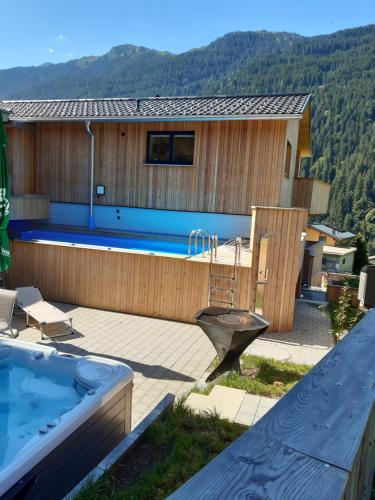 a house with a large swimming pool next to a house at Appartement Anemone in Sankt Gallenkirch