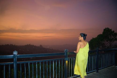 a woman in a yellow dress standing on a fence at Eye Catch Kandy in Kandy