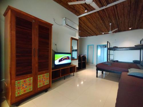 a living room with a tv and a bed and a couch at The Baga Village-TBV in Baga