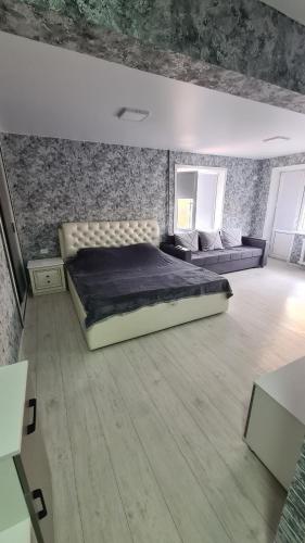 a bedroom with a large bed and a couch at Сдаётся однокомнатная квартира Люкс возле озера. in Balqash