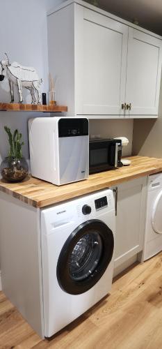 a kitchen with a washing machine and a microwave at La Casa Rossa with free parking in Cheltenham