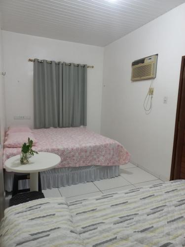 a bedroom with two beds and a table and a bed at Pousada Residencial acochego caririense in Juazeiro do Norte