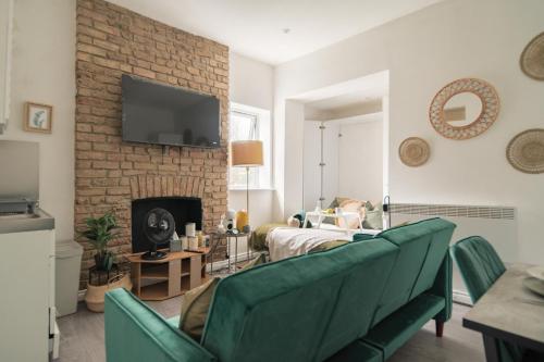 a living room with green chairs and a fireplace at Livestay-Studio Apartments in London Green Lanes in London